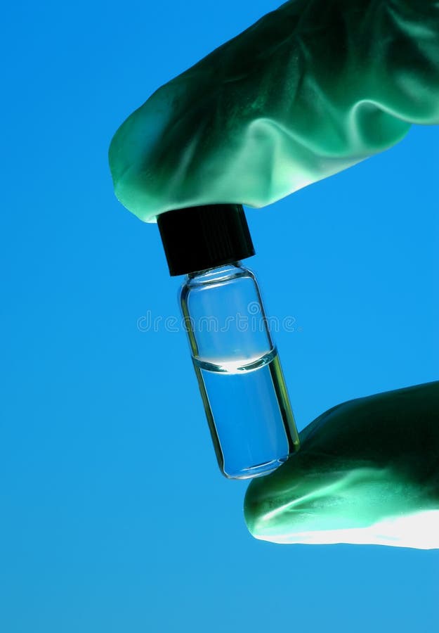 Gloved hand holding vial with clear liquid. Gloved hand holding vial with clear liquid