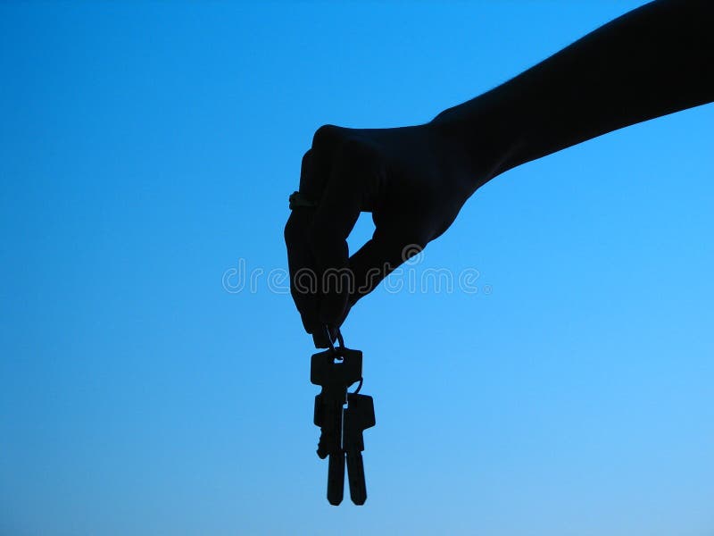 Hand holding keys,blue skies in the background. Hand holding keys,blue skies in the background