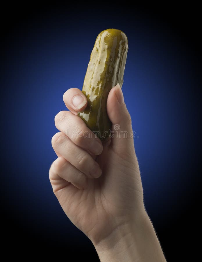 Hand holding a pickle in the studio with a blue glow background. Hand holding a pickle in the studio with a blue glow background.