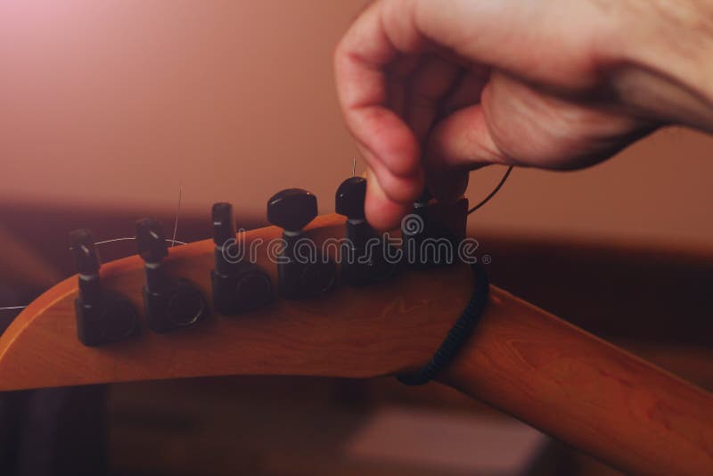Ręka muzyka tuningowa gitara w ciemności studio muzycznego. Dłoń muzyka tuning gitarę w ciemności studia muzycznego toned background