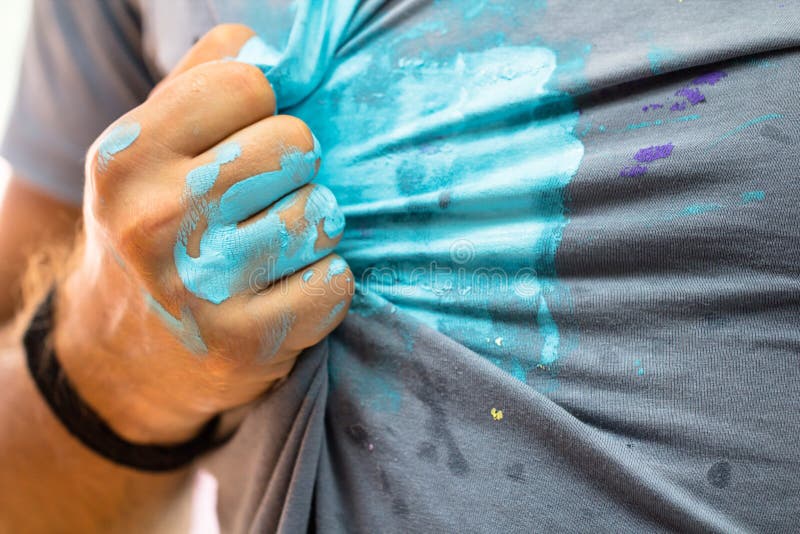 Man hand stained by a blue paint wipe out the color of a shirt as artist, worker, creative hobby concept background. Man hand stained by a blue paint wipe out the color of a shirt as artist, worker, creative hobby concept background