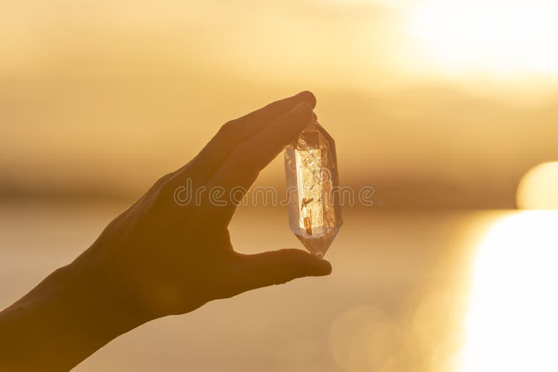Ręka trzyma up pięknego kwarcowego kryształ outdoors w słońcu fotografia stock Ręka trzyma up pięknego kwarcowego kryształ outdoors w słońcu fotografia stock