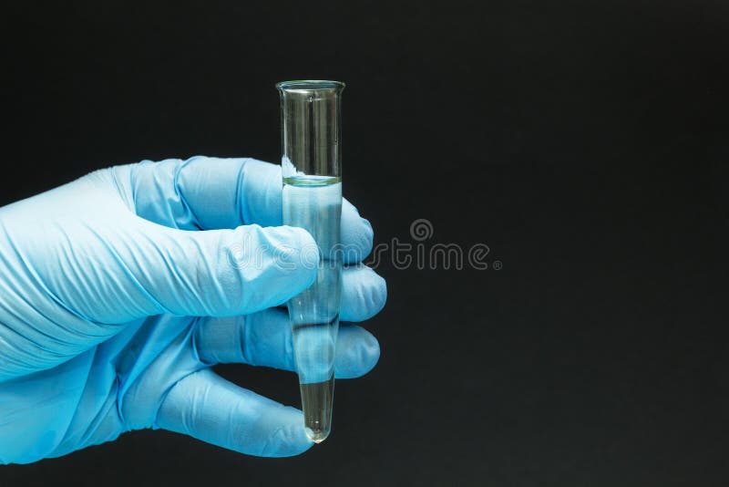 Ręka w błękitnej rękawiczce trzyma homeopatycznego remedium w szklanej tubce na czarnym tle, w górę zdjęcia royalty free Ręka w błękitnej rękawiczce trzyma homeopatycznego remedium w szklanej tubce na czarnym tle, w górę zdjęcia royalty free