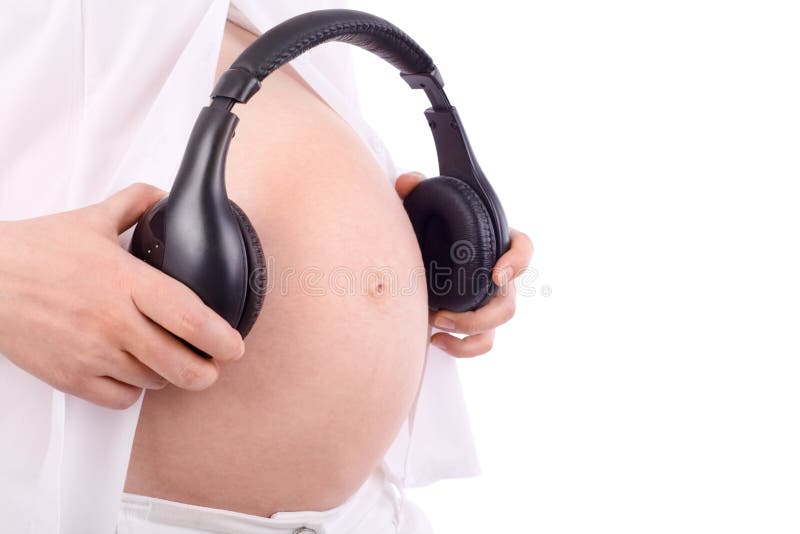Hands of pregnant woman in white holding black headphones close to belly isolated on white background. Hands of pregnant woman in white holding black headphones close to belly isolated on white background.