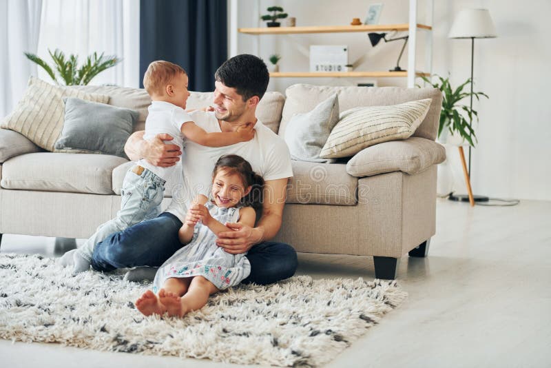 S'assoit sur le sol. homme avec son petit fils et sa fille à la maison images stock