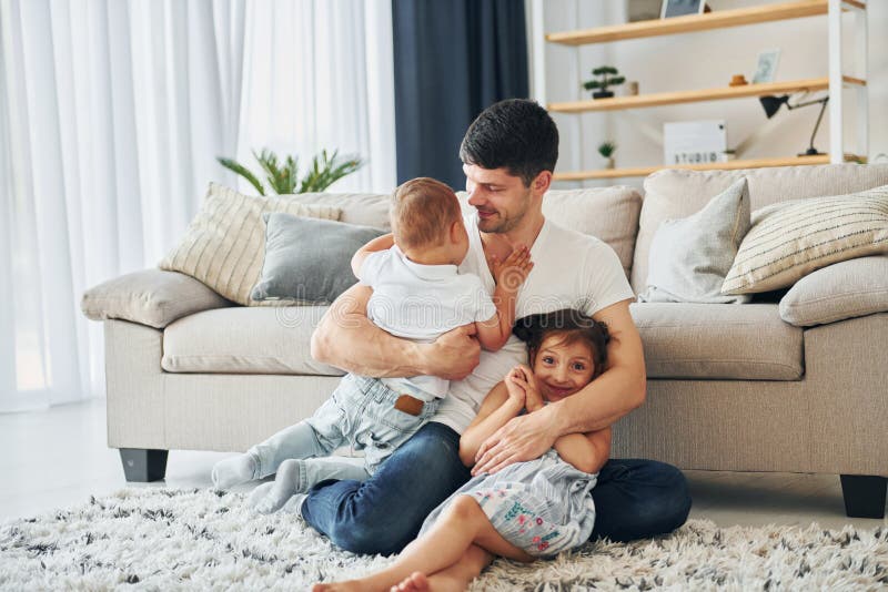 S'assoit sur le sol. homme avec son petit fils et sa fille à la maison photo stock