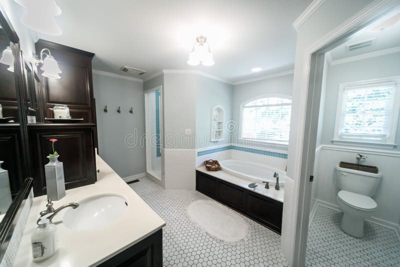 1950`s style bathroom with tile floor and dark brown cabinets in white and blue accents