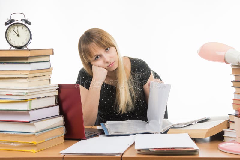 Saaie studenten het document doorbladert bij lijst onder boeken en stapels blikken in het beeld royalty-vrije stock afbeelding Saaie studenten het document doorbladert bij lijst onder boeken en stapels blikken in het beeld royalty-vrije stock afbeelding