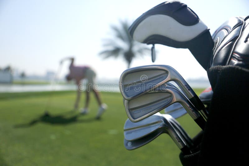 Sac de golf avec des clubs sur le plan et avec le joueur avant oscillation à l'arrière-plan photos stock Sac de golf avec des clubs sur le plan et avec le joueur avant oscillation à l'arrière-plan photos stock