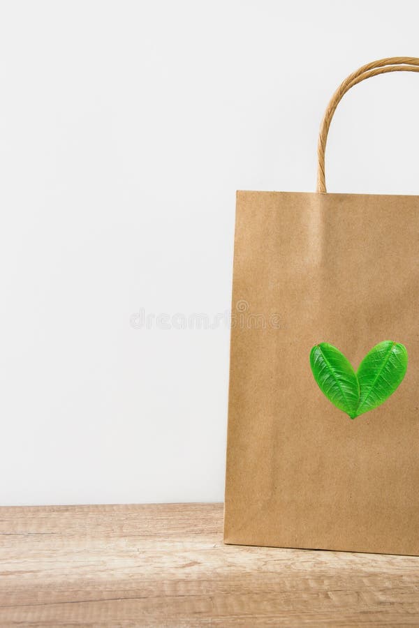 Sac de papier brun vide de métier sur le fond blanc de mur Logo de coeur des feuilles Style amical de nature Conservation environ image stock Sac de papier brun vide de métier sur le fond blanc de mur Logo de coeur des feuilles Style amical de nature Conservation environ image stock