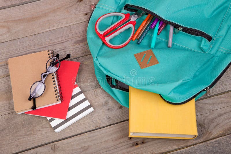 Sac à dos et fournitures scolaires : livres, crayons, bloc-notes, stylos feutres, lunettes, ciseaux sur la table en bois images libres de droits Sac à dos et fournitures scolaires : livres, crayons, bloc-notes, stylos feutres, lunettes, ciseaux sur la table en bois images libres de droits