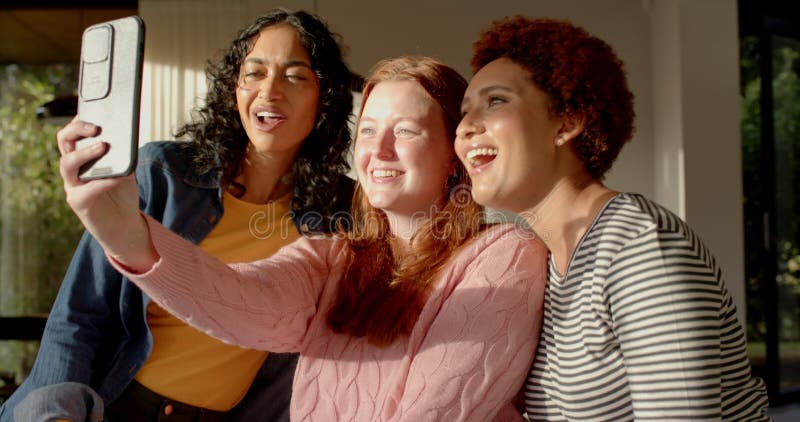 Sacando selfies con diversas amigas, sonriendo y disfrutando del tiempo juntos en el interior almacen de metraje de vídeo