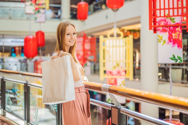 Sacchetto della spesa della tenuta della donna contro lo sfondo delle lanterne rosse cinesi per il nuovo anno cinese Grande vendi immagine stock libera da diritti Sacchetto della spesa della tenuta della donna contro lo sfondo delle lanterne rosse cinesi per il nuovo anno cinese Grande vendi immagine stock libera da diritti