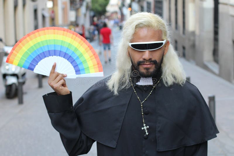 Sacerdote de mirada futurista que sostiene una fan del arco iris fotografía de archivo libre de regalías Sacerdote de mirada futurista que sostiene una fan del arco iris fotografía de archivo libre de regalías