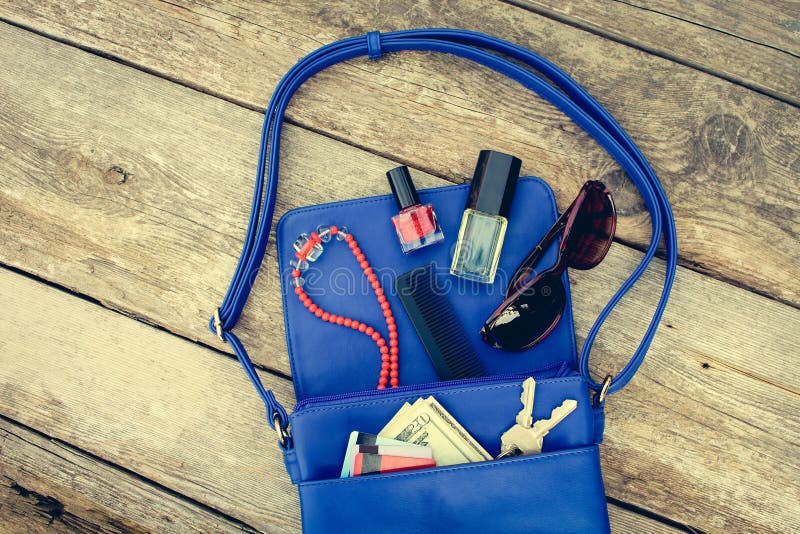 Sachen von offenem Damengeldbeutel Kosmetik, Geld und Frauen ` s Zubehör fielen aus blauer Handtasche heraus lizenzfreies stockbild Sachen von offenem Damengeldbeutel Kosmetik, Geld und Frauen ` s Zubehör fielen aus blauer Handtasche heraus lizenzfreies stockbild