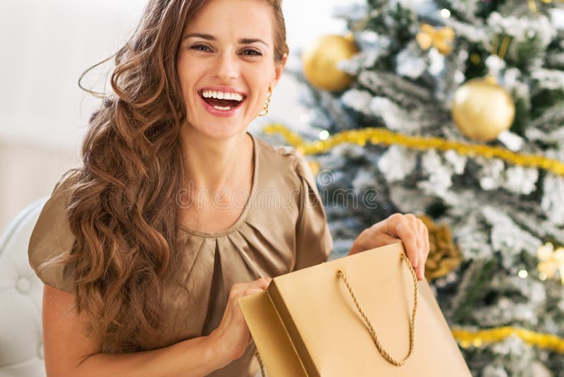 Saco de compras feliz da abertura da jovem mulher perto da árvore de Natal fotografia de stock