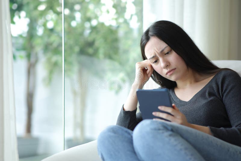 Sad asian woman reading ebook sitting at home stock image
