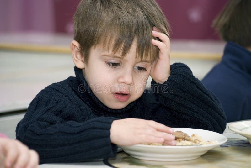 Triste chico tiene no querer sobre el comer sobre el jardín de infancia.