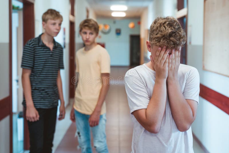 Sad bullied boy standing n the school corridor