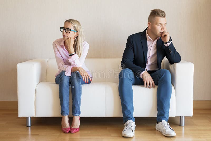 Sad couple sitting on couch and looking in different directions