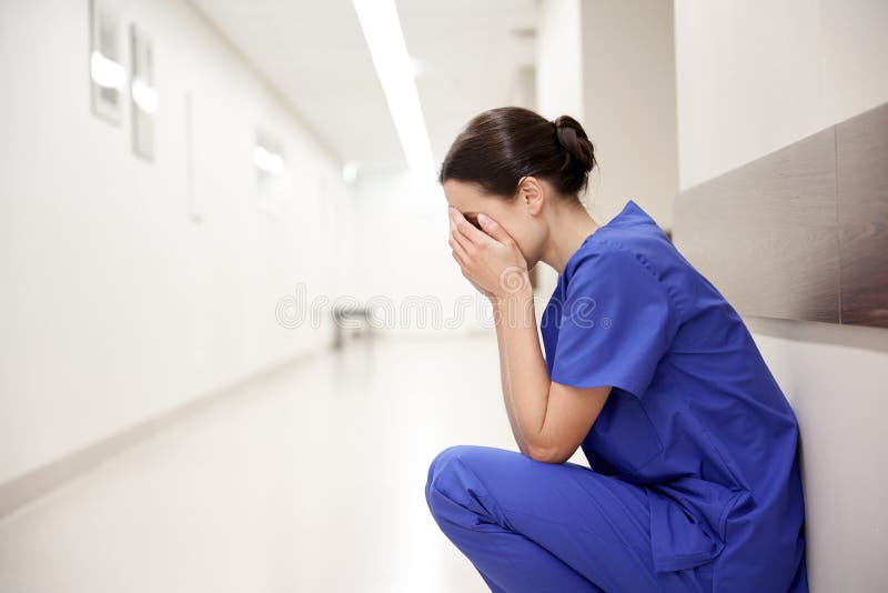 Sad or crying female nurse at hospital corridor