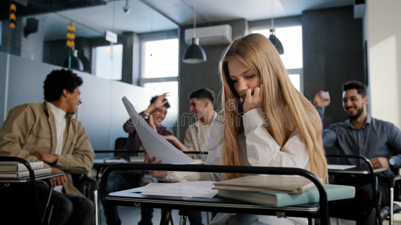 Sad frustrated insecure girl student sitting in classroom at desk suffering from abuse bad attitude ridicule from