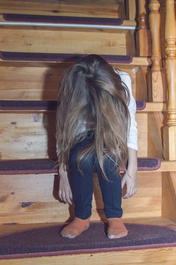 Sad Girl Sitting On The Stairs With Her Hands Down And Her Head