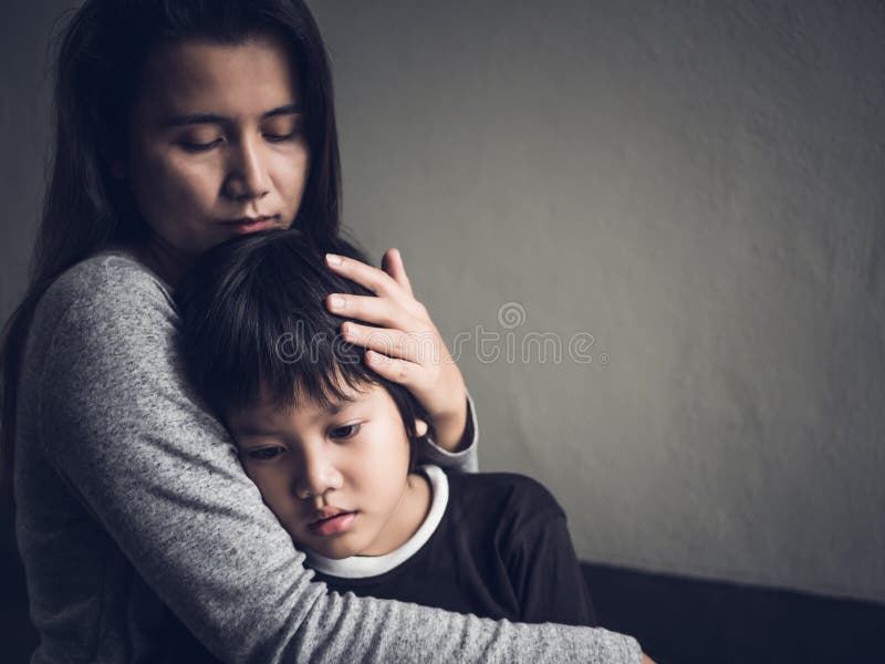 Sad little boy being hugged by his mother at home.