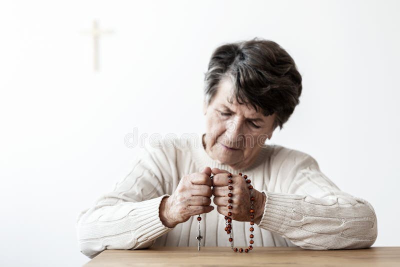 Sad and lonely grandmother with rosary praying to god in the church royalty free stock photo Sad and lonely grandmother with rosary praying to god in the church royalty free stock photo