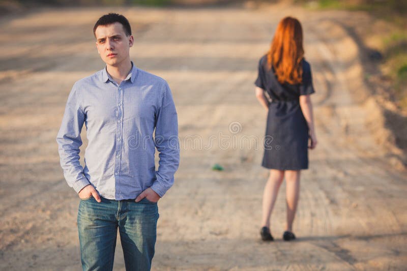 Sad man and woman stand on the dirt road