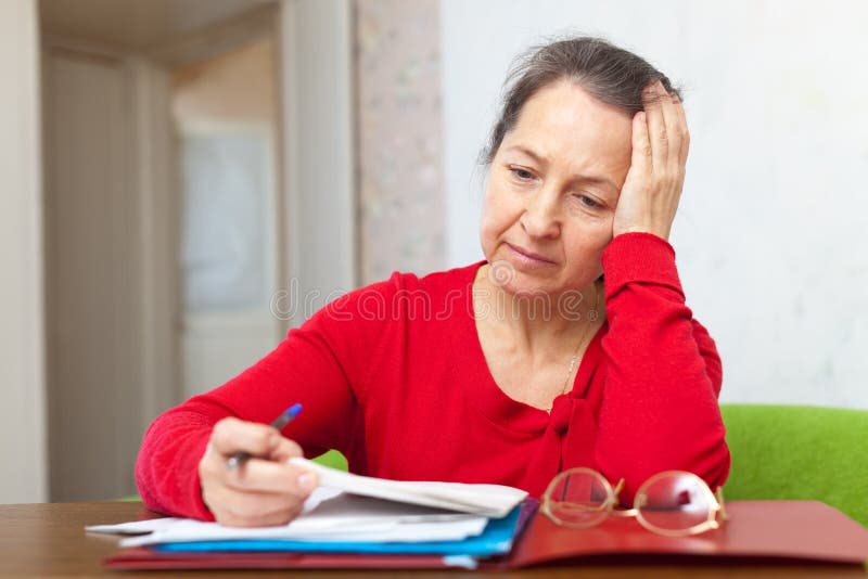 Sad mature woman reads documents at home