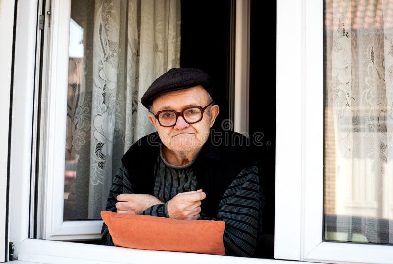 Senior man looking out of window in a loft flat stock photo