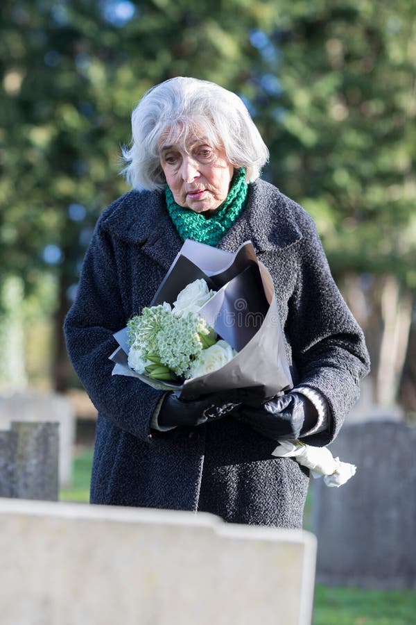 Sad Senior Woman With Flowers Standing By Grave royalty free stock image Sad Senior Woman With Flowers Standing By Grave royalty free stock image