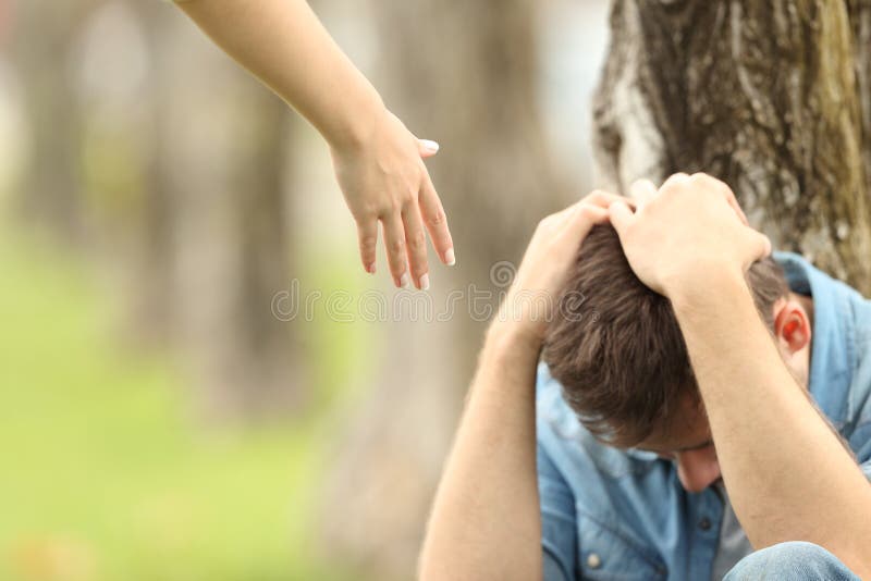 Sad teen sitting on the grass in a park and a women hand offering help with a green background. Sad teen sitting on the grass in a park and a women hand offering help with a green background