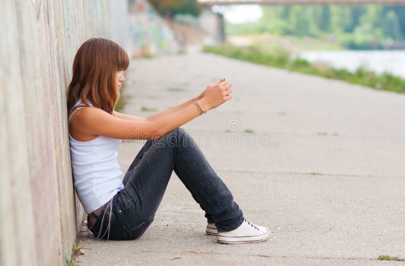 Sad teenage girl sitting alone in urban environmen