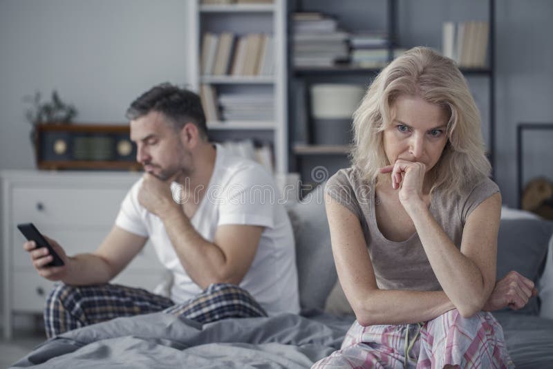 Stressed, sad wife and her cheating husband in the bedroom. Stressed, sad wife and her cheating husband in the bedroom