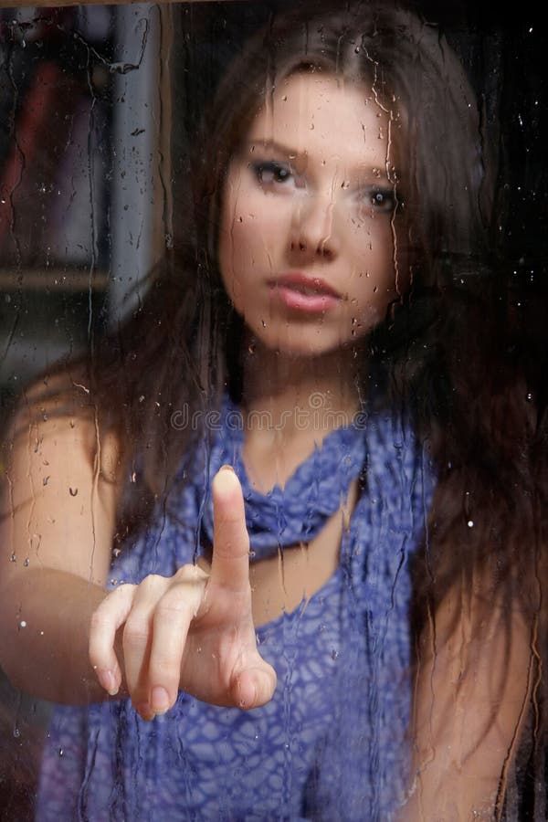 Sad woman behind wet window