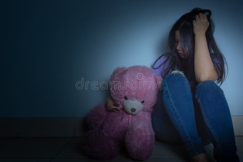 sad woman hug her knee and cry sitting with teddy bear in a dark room. Depression, unhappy, stressed and anxiety disorder concept