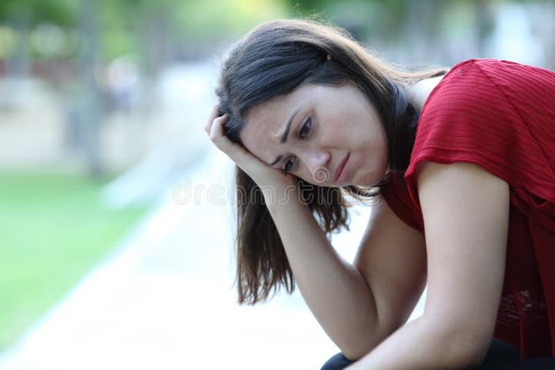 Sad woman sitting in a park looking away