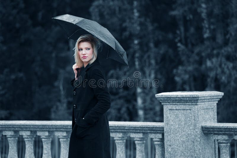 Smutné mladý módní blond žena s deštníkem venku.