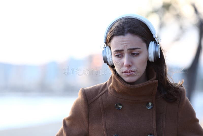 Sad woman walking listening to music alone in winter