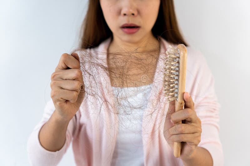 Sad young Asian girl looking at her hair loss with shock isolated on white background