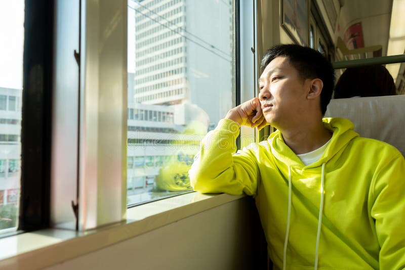 Sad young asian man looking through the window in the train carriage