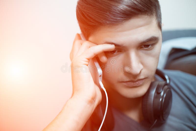 Sad Young Man Talking on the Phone with Headphones on Neck. Stock Image