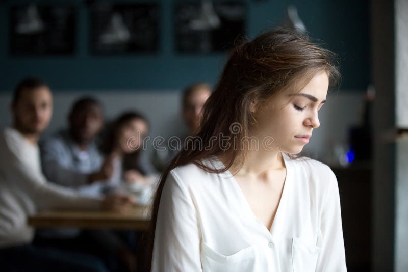Sad young woman avoiding friends suffering from gossiping or bul