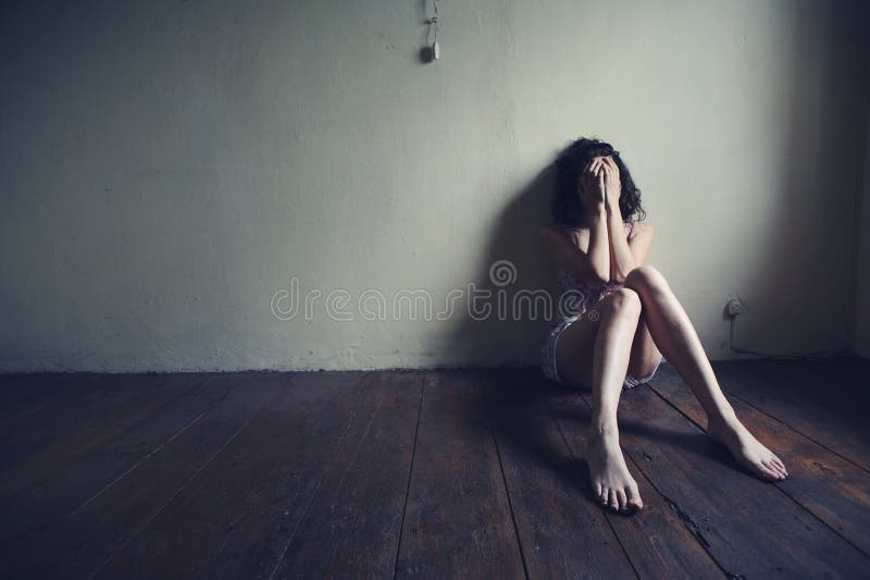 Smutná žena sedí sám v prázdné místnosti.