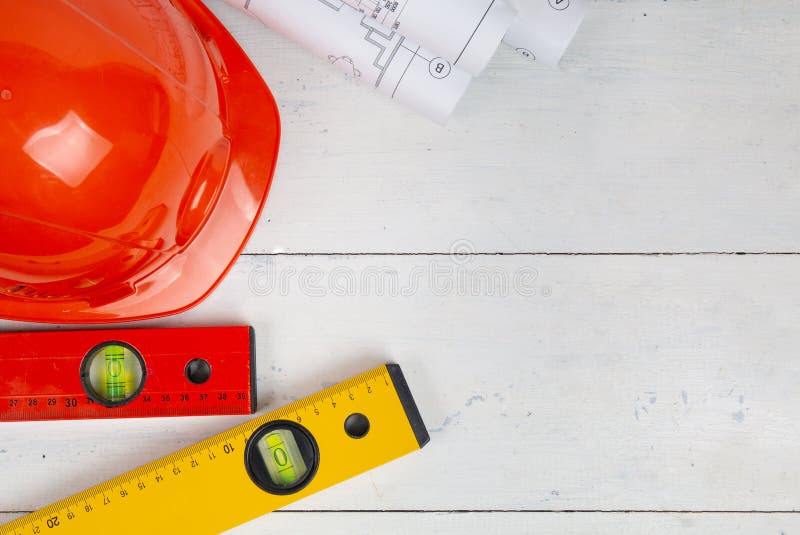 Safety helmet, paper drawings, blueprints and building level on a white table. The work of a civil engineer. stock photo