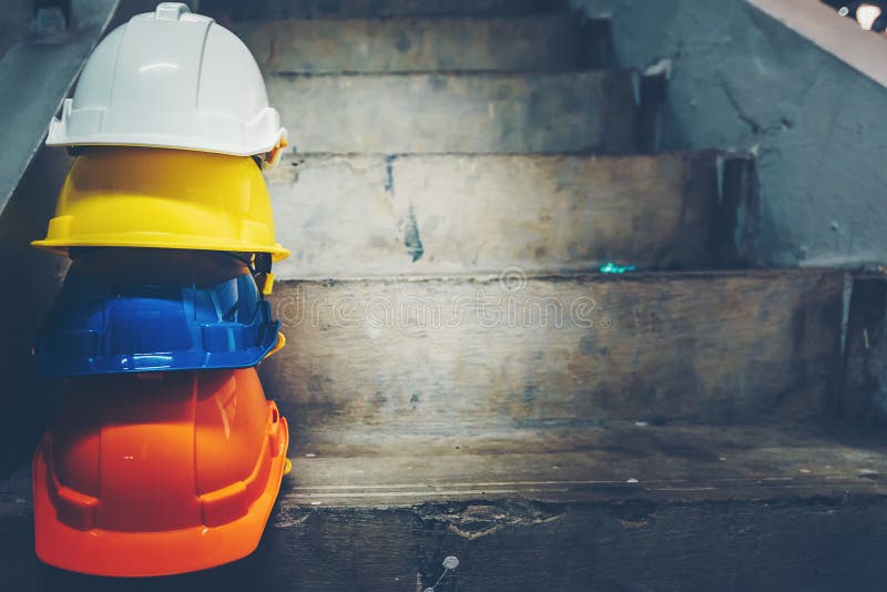 Safety helmet, white, yellow, blue and orange, placed on the cement floor in the construction site