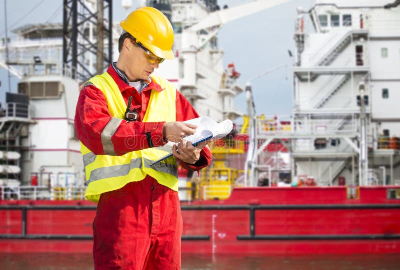 Safety officer. Standing in front of a huge industrial platform, wearing overalls, a hard hat, safety goggles, and holding a clipboard with checklists royalty free stock images Safety officer. Standing in front of a huge industrial platform, wearing overalls, a hard hat, safety goggles, and holding a clipboard with checklists royalty free stock images