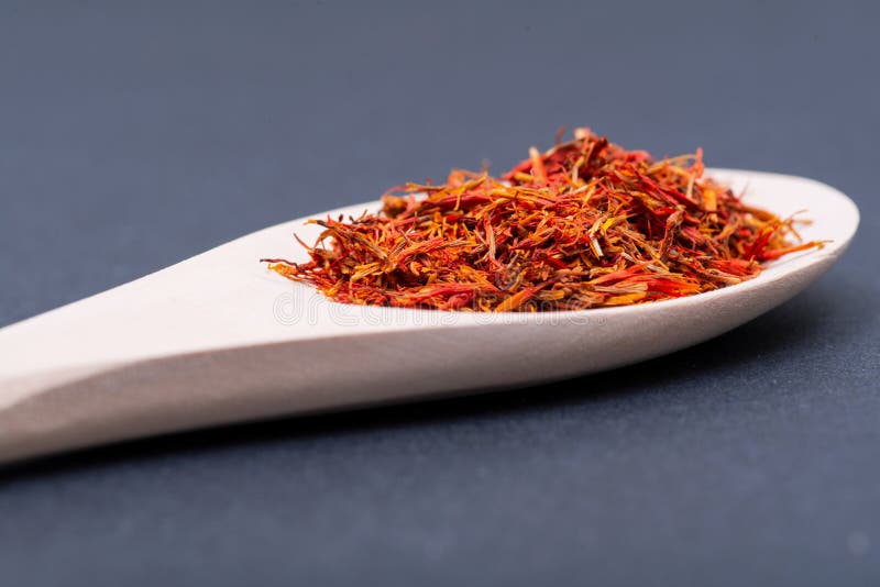 Saffraankruid van de Sativus bloem van Krokus, die algemeen als de ?saffraankrokus ?wordt bekend, in houten lepel op dark stock afbeelding Saffraankruid van de Sativus bloem van Krokus, die algemeen als de ?saffraankrokus ?wordt bekend, in houten lepel op dark stock afbeelding